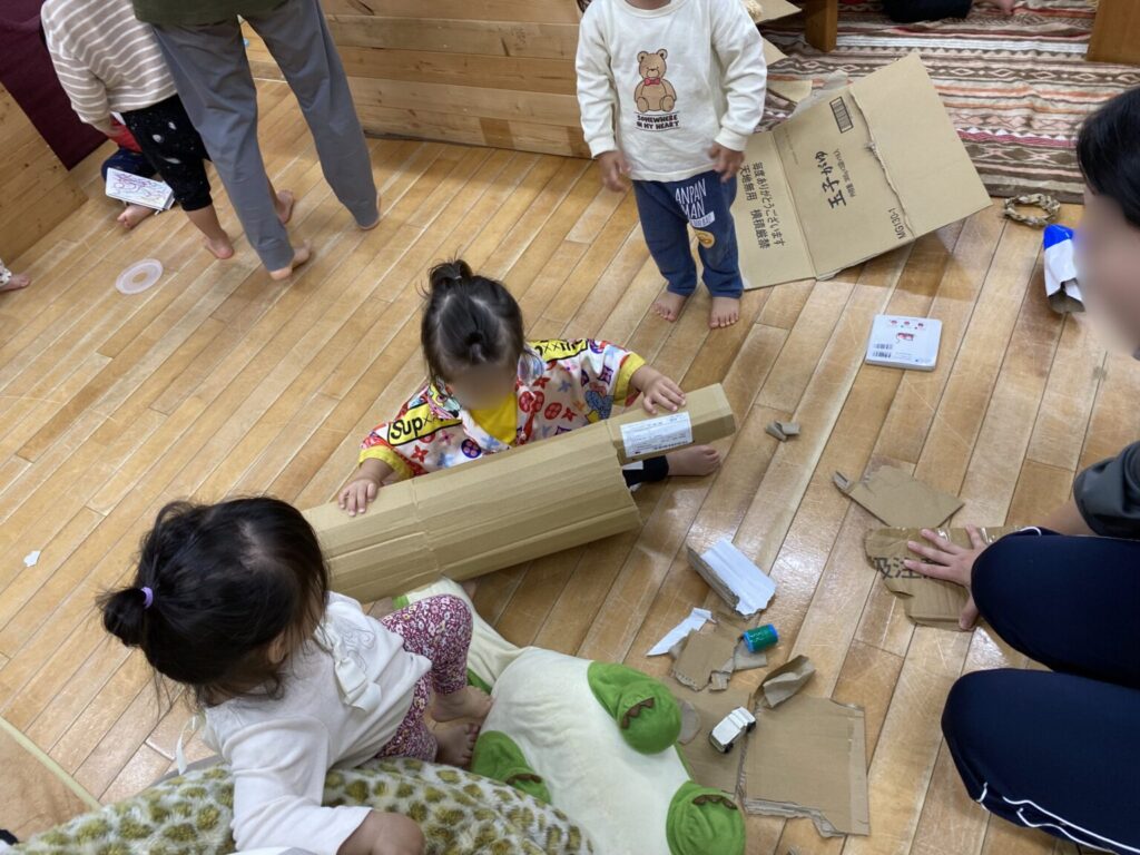 保育室でダンボールを使って遊ぶこどもたち