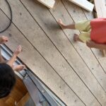 木屑が残る床に触れるこどもの手足。