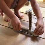 木の枝と輪切りの木を組み合わせたキックスクーターを扱うこどもの手